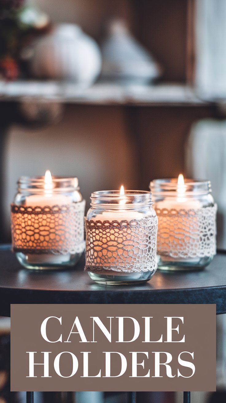 Three lit candles in glass jars decorated with lace, placed on a dark round table. The background is soft-focused featuring shelves and a blurred item, creating a cozy ambiance. CANDLE HOLDERS text is displayed at the bottom of the image.